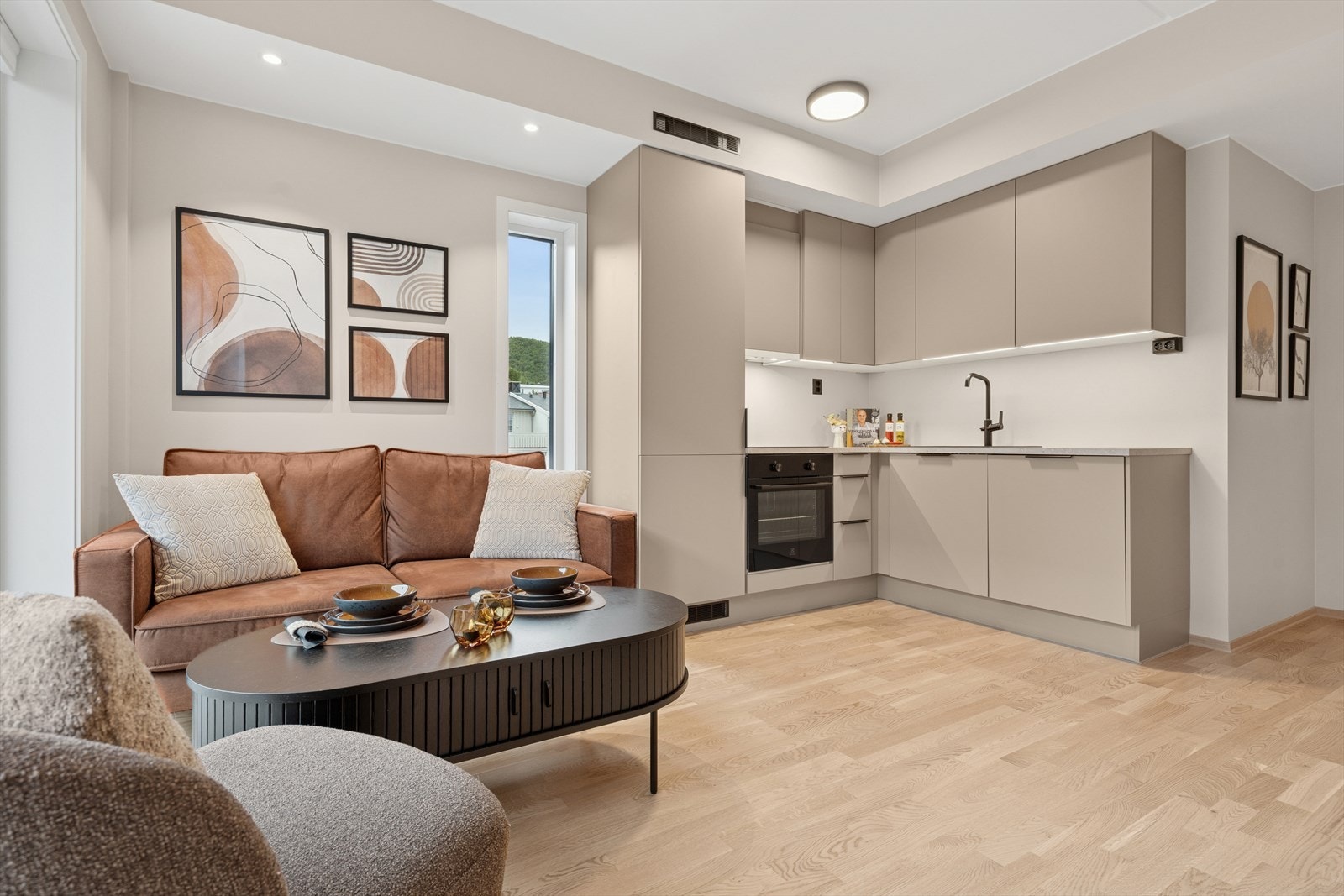 Stue/kjøkken har fin belysning med downlights, taklamper og lys under overskapene på kjøkkenet Galleribilde