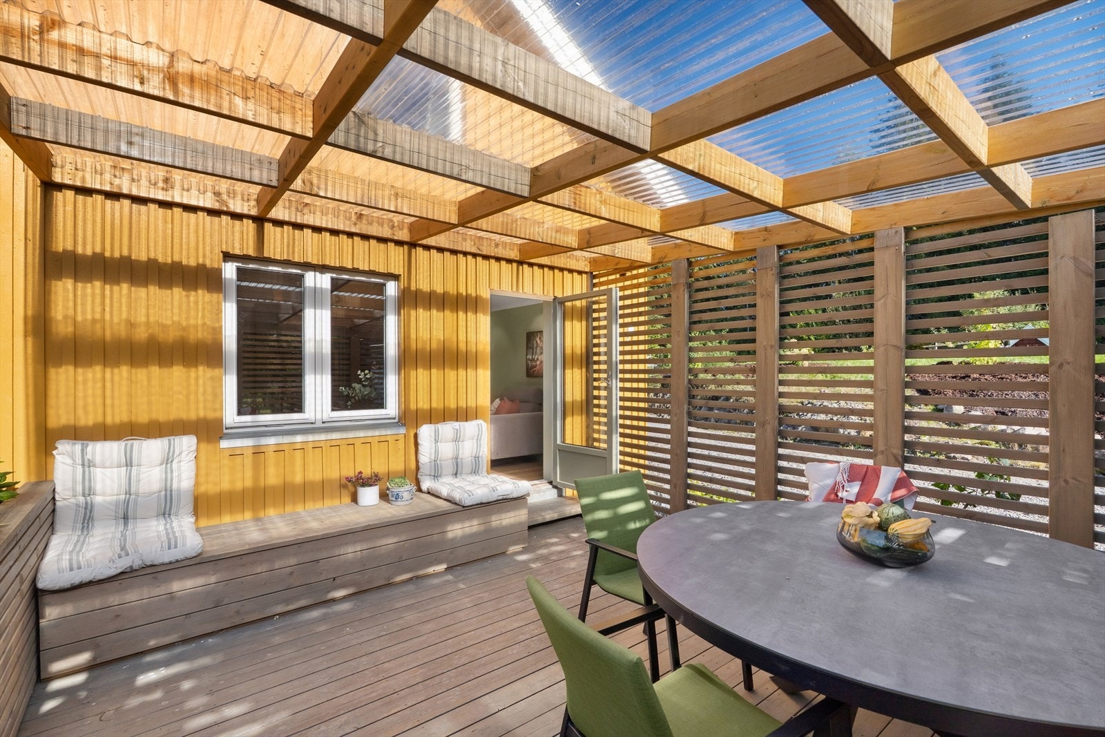 Delvis o
verbygd terrasse med gjennomsiktig tak gir ly for regn og ekstra lys til uteplassen. Galleribilde