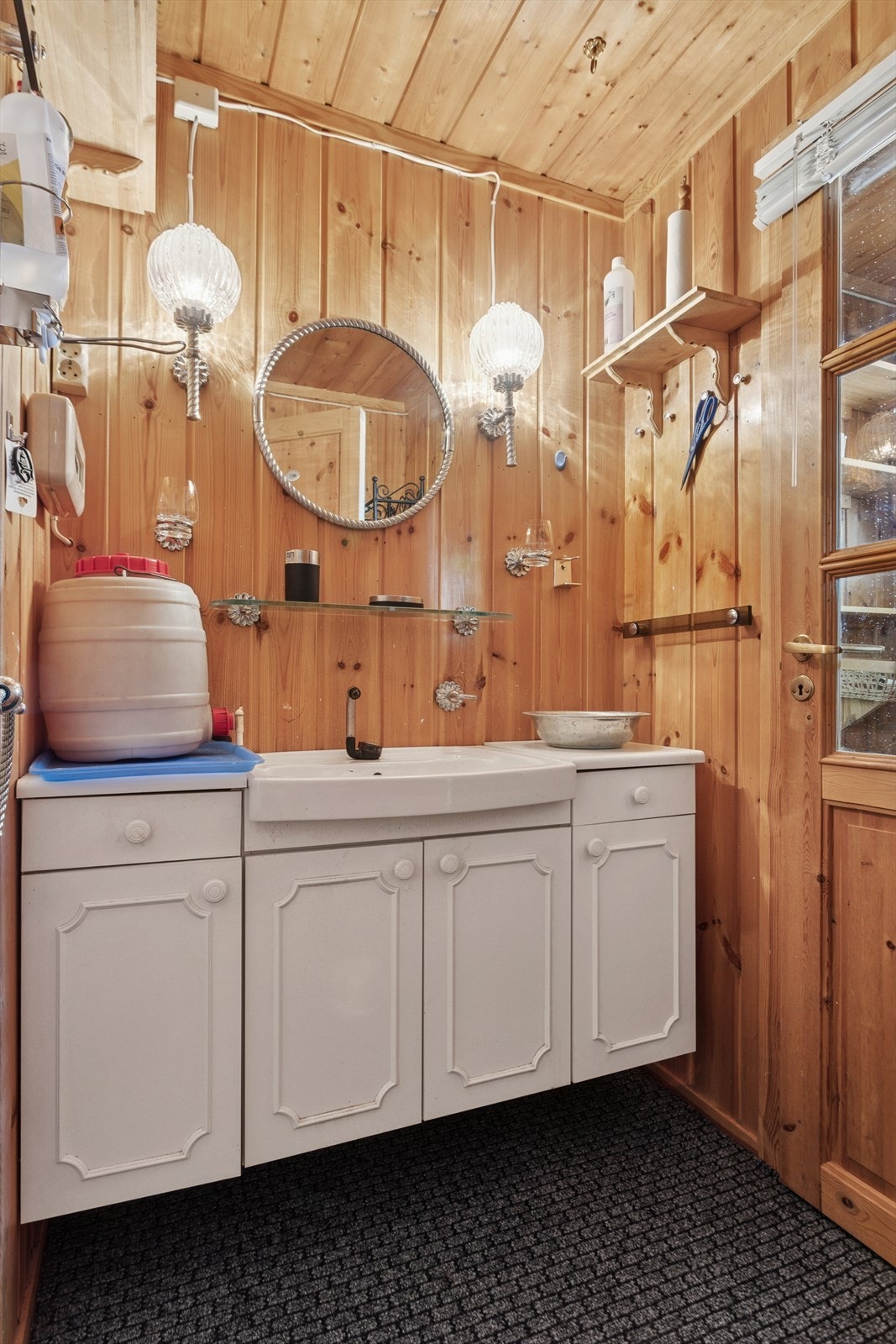 Baderomsinnredning med profilerte fronter, laminat benkeplate og servant med gråvann til grunn. 12V pumpe på kran og tank i benk. Galleribilde