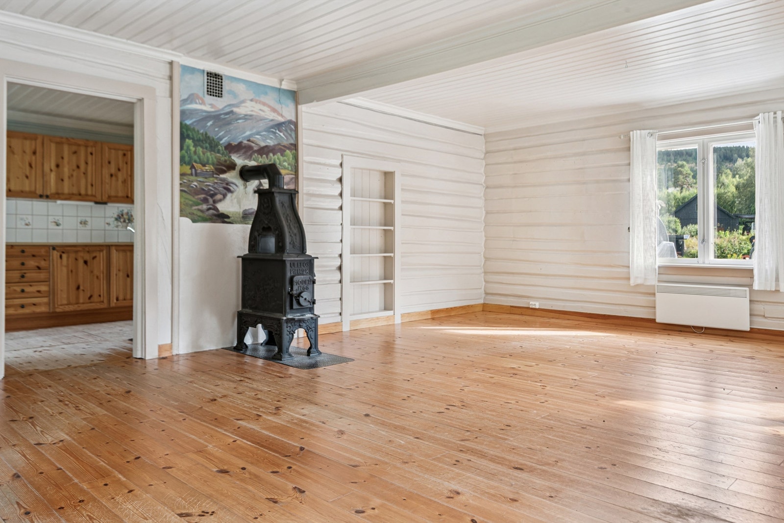 Stuen er et sentralt rom med tømmervegger og furugulv. En vedovn gir ekstra varme og atmosfære. Galleribilde