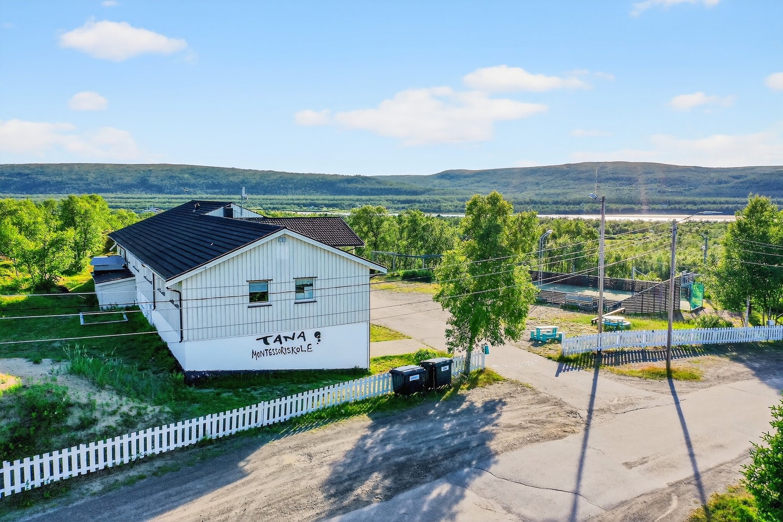 Fasade av Tana Montesoriskole. Parkering og innkjøring til skole. I bakgrunn Vestre Seida. Galleribilde