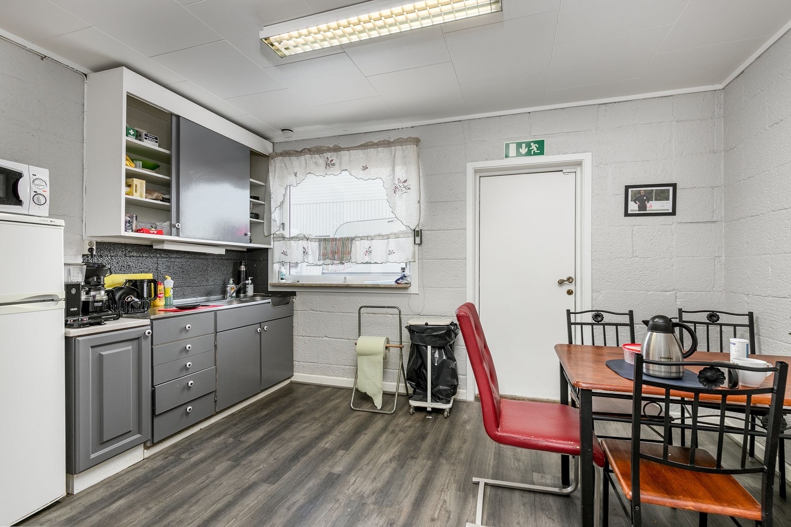 Kjøkkeninnredning med glatte fronter. Benkebeslag i rustfritt stål med utslagskum og kum. Galleribilde