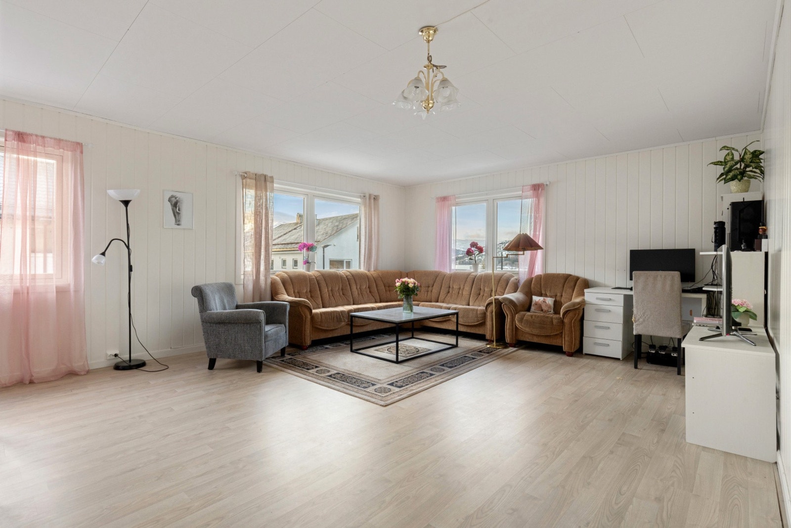 Stor og romslig stue som får godt med naturlig lys in fra store vindusflater Galleribilde