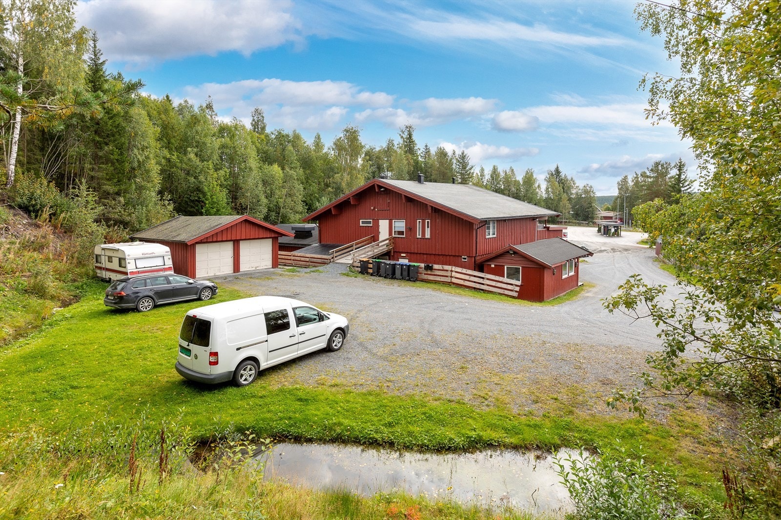 Eiendommen sett bakfra. Inngangsparti til leilighetene. Garasje med plass til to biler. Galleribilde