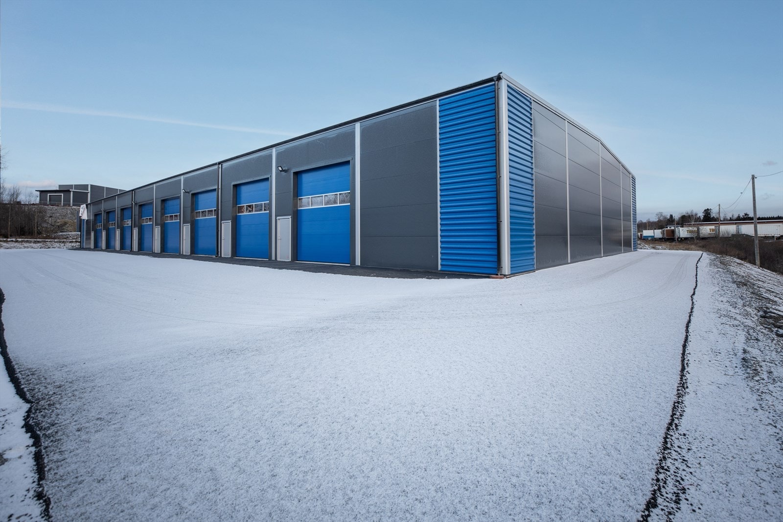 En elektrisk leddheisport med b x h = 4m x 4,4m pr. seksjon. Port leveres med vindu og en fjernkontroll. Bygget er isolert. Innvendig fri høyde til takplater er 6 meter. Galleribilde