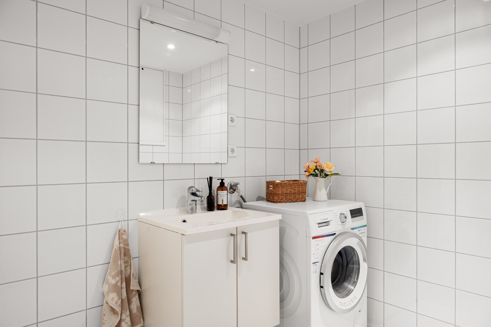 Badet er innredet med vask i seksjon, speil, dusjhjørne og vegghengt toalett. Galleribilde