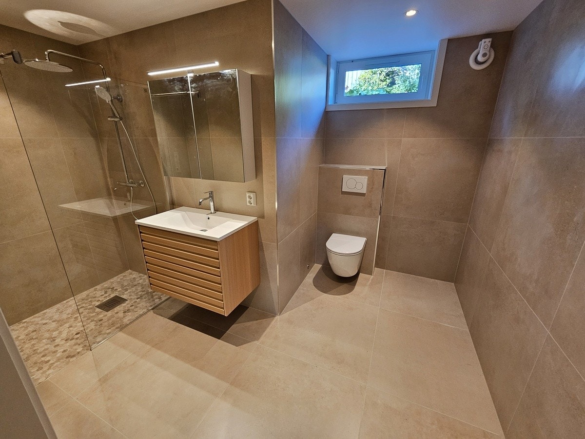 Over til badene. Begge badene er totalrenovert våren 2024. Det første badet består av dusjnisje, servant, servantskap, speilskap og vegghengt toalett. Automatisk fuktstyring og varmekabler i gulv. Galleribilde