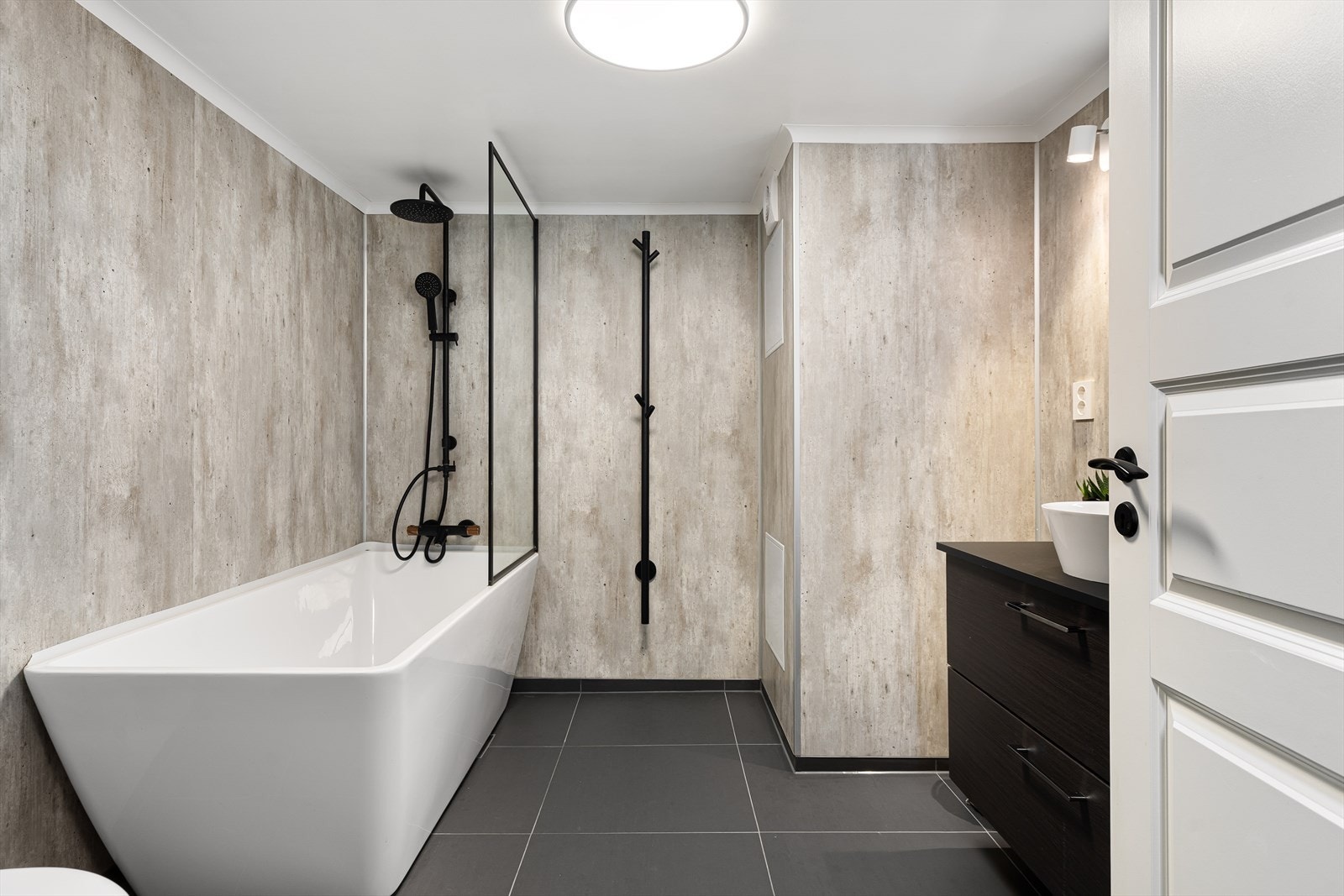 Boligen har et lekkert Flislagt bad i kjeller med termostatstyrt gulvvarme, vegghengt toalett og stilrent servantskap med speil og lys. Våtromsplater på veggene Galleribilde