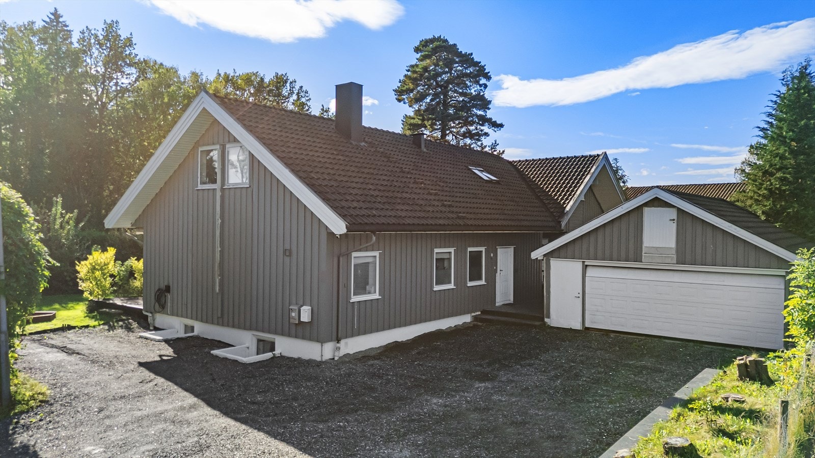 Gruset felles gårdsplass. Parkering på kortsiden av boligen. Garasjen tilhører naboseksjonen. Galleribilde