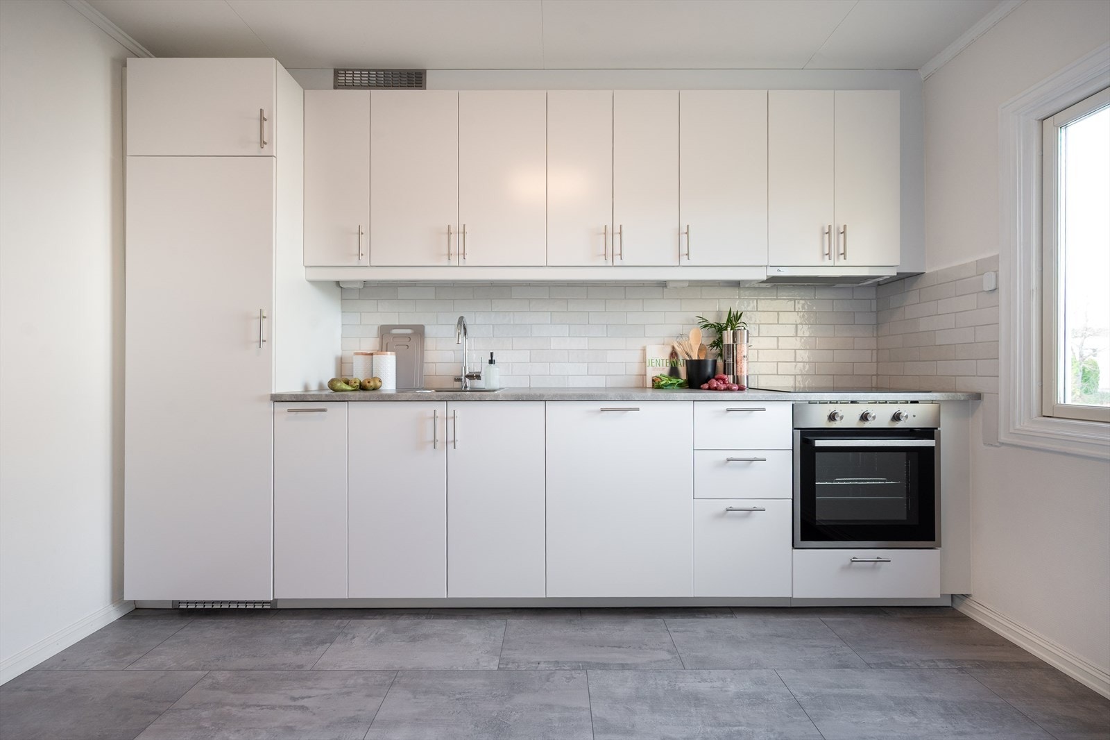 Nytt IKEA-kjøkken med integrerte hvitevarer. Rommet har plass til et lite spisebord og gir en fin forbindelse mot resten av første etasje. Galleribilde