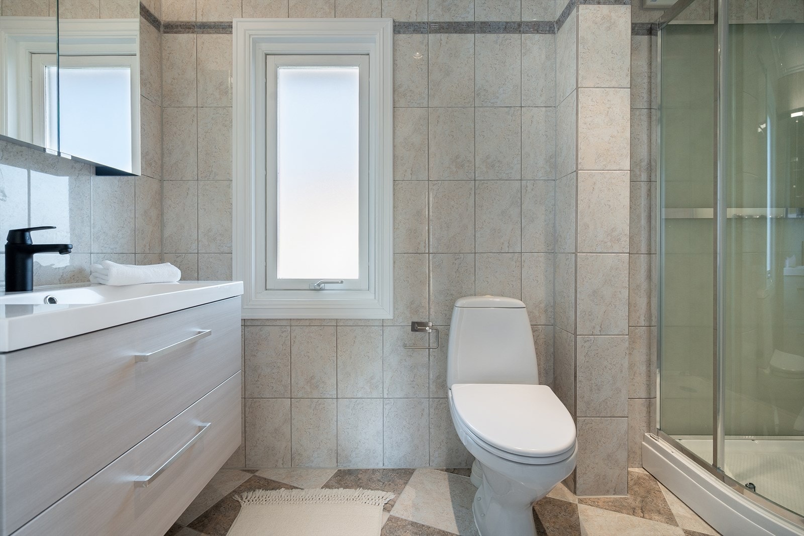 Lyst og praktisk bad med fliser på vegger og gulv, oppgradert innredning fra 2025 og egen dusjkabinett-løsning. Et funksjonelt rom plassert samlet med soverommene i andre etasje. Galleribilde