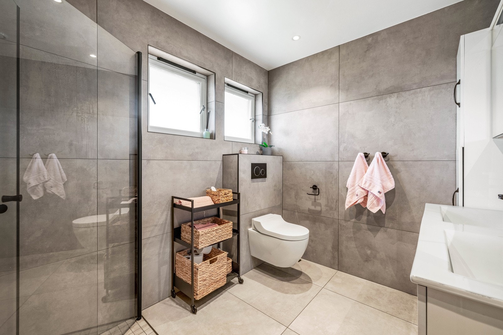 Badet har store fliser på vegger og gulv, og underliggende varmekabler i gulvet. Galleribilde