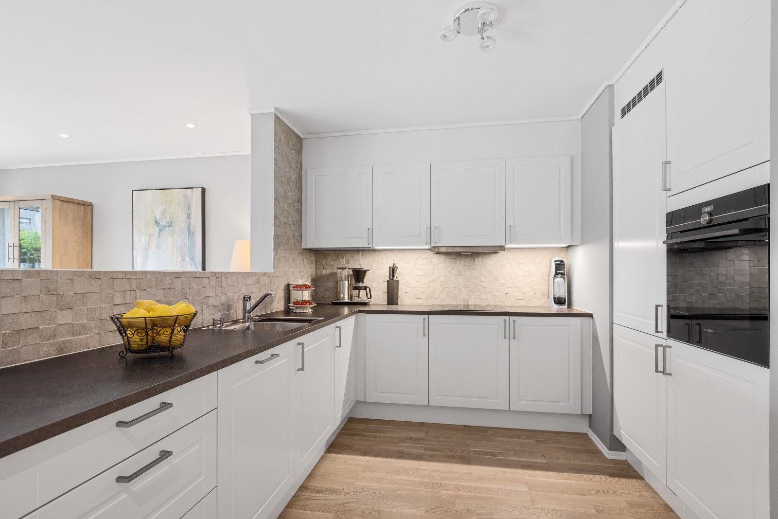 Det stilrene HTH-kjøkkenet er valgt som tilvalg ved oppføringen av bygget. I tillegg er det lagt mosaikkfliser mellom overskap og benkeplate, noe som gir et eksklusivt og gjennomført uttrykk. Galleribilde