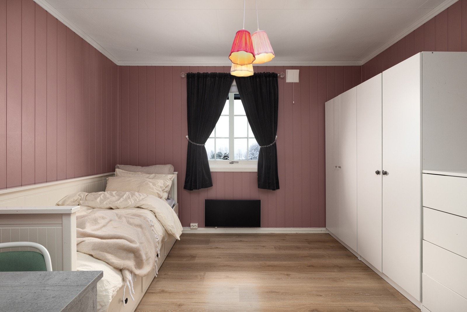 Romslig soverom med lune rosafargede vegger, store garderobeskap og dagslys fra vinduet. Galleribilde