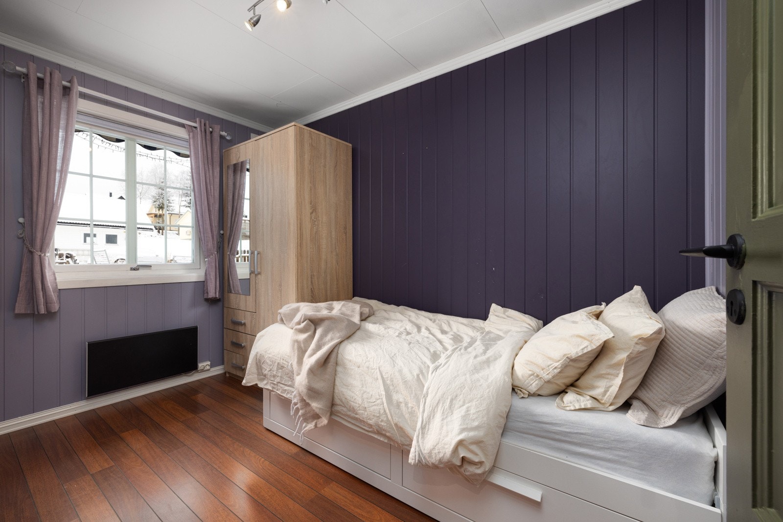 Hyggelig soverom med mørke lillatoner, dagsys fra vinduet og praktisk garderobeløsning. Galleribilde