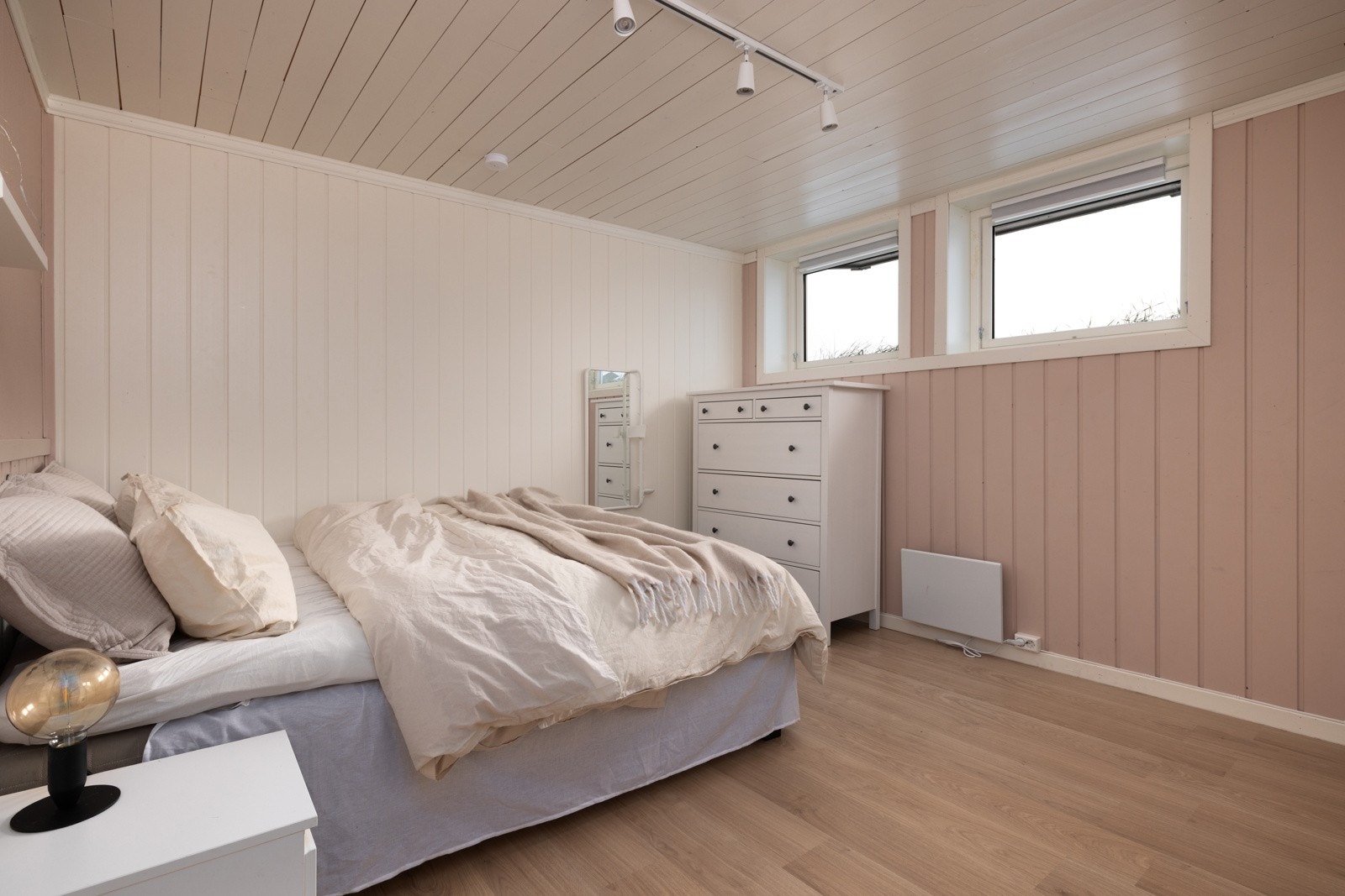 Lyst og romslig soverom med delikate pastellfarger og store vinduer som slipper inn naturlig lys. Galleribilde