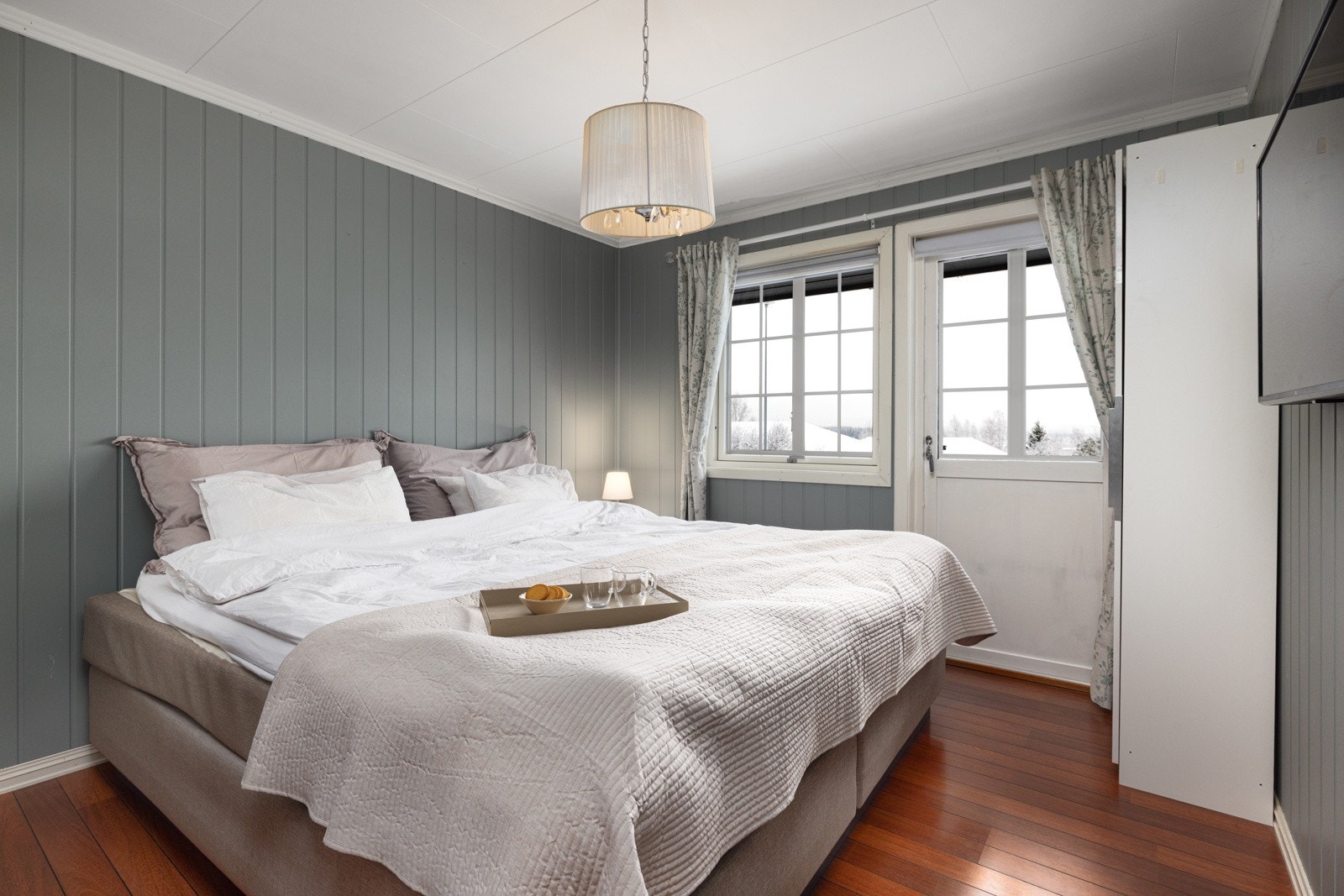 Lyst og innebydende soverom med panelvegger og utgang til balkong. Galleribilde