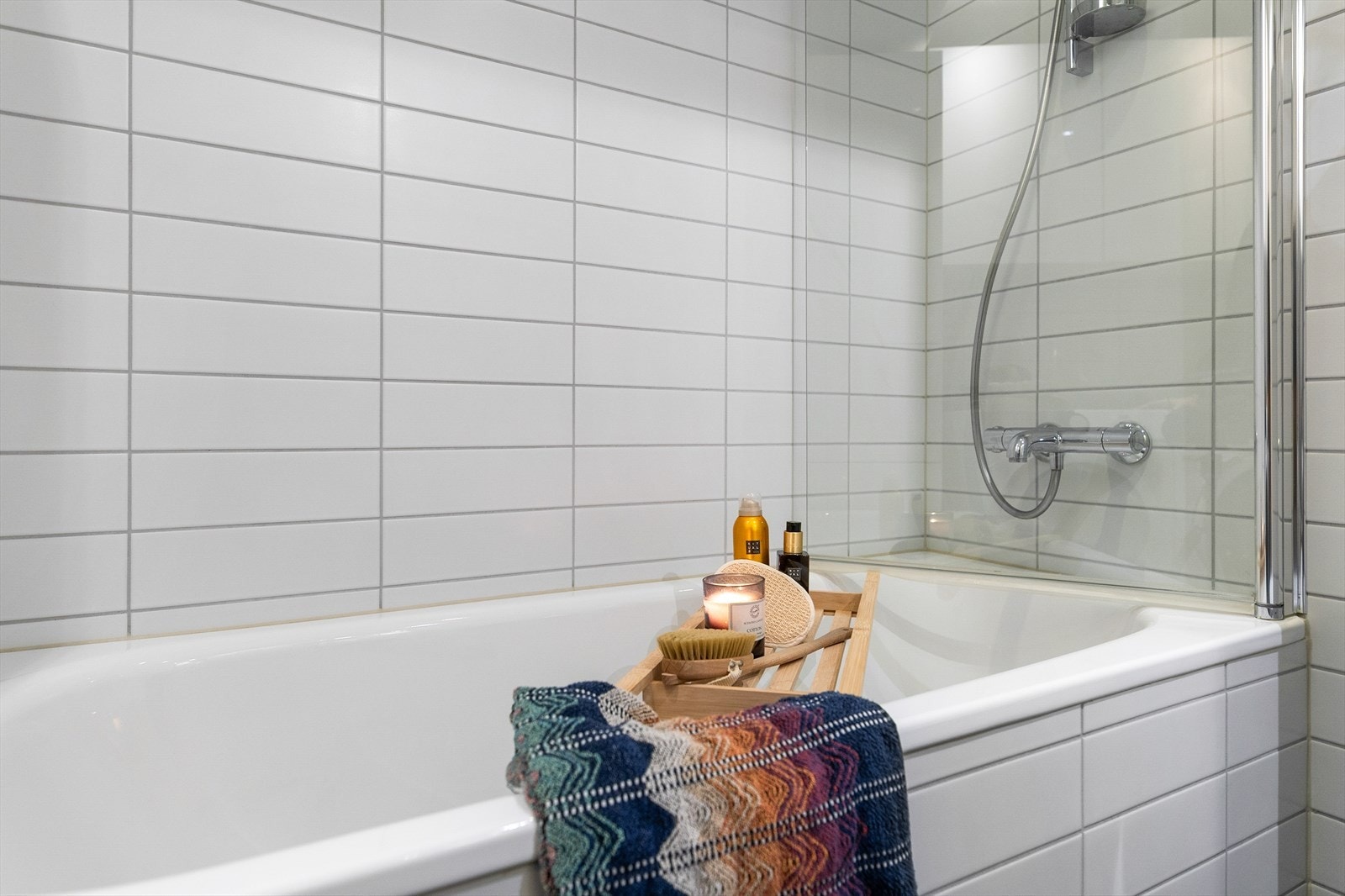 Badet er innredet med vegghengt toalett, badekar og baderomsinnredning Galleribilde