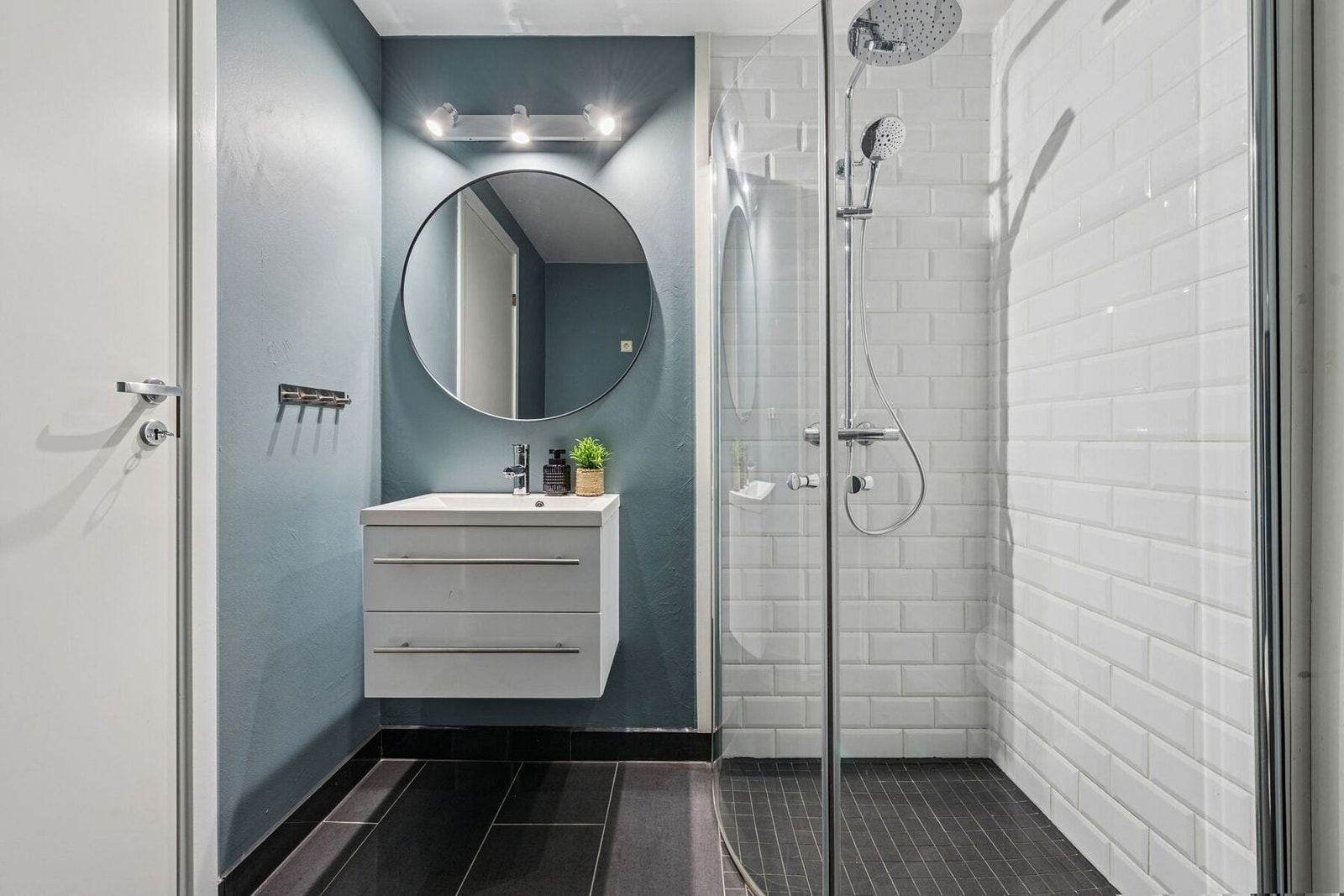 Badet har en deilig dusjsone, skjermet med vendbare dusjdører i herdet glass. Det er satt inn nytt dusjgarnityr i 2025 med både regnfalls- og hånddusj. Galleribilde