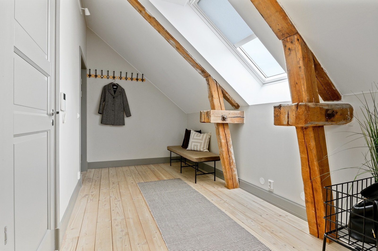 Innenfor døren blir du møtt av entréen som har tregulv og synlige trebjelker som er gjennomgående for resten av leiligheten. Galleribilde