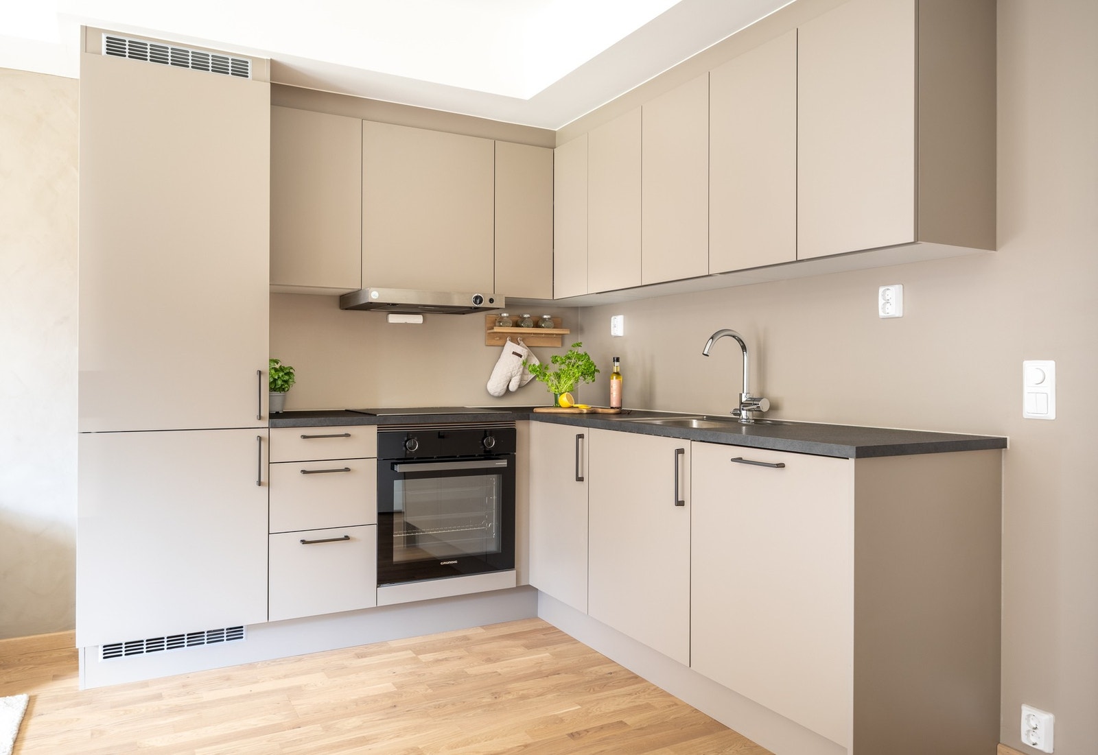 Tidsmessig innredning fra byggeår med grå, glatte fronter og laminert benkeplate med nedfelt oppvaskkum av rustfritt stål. Galleribilde