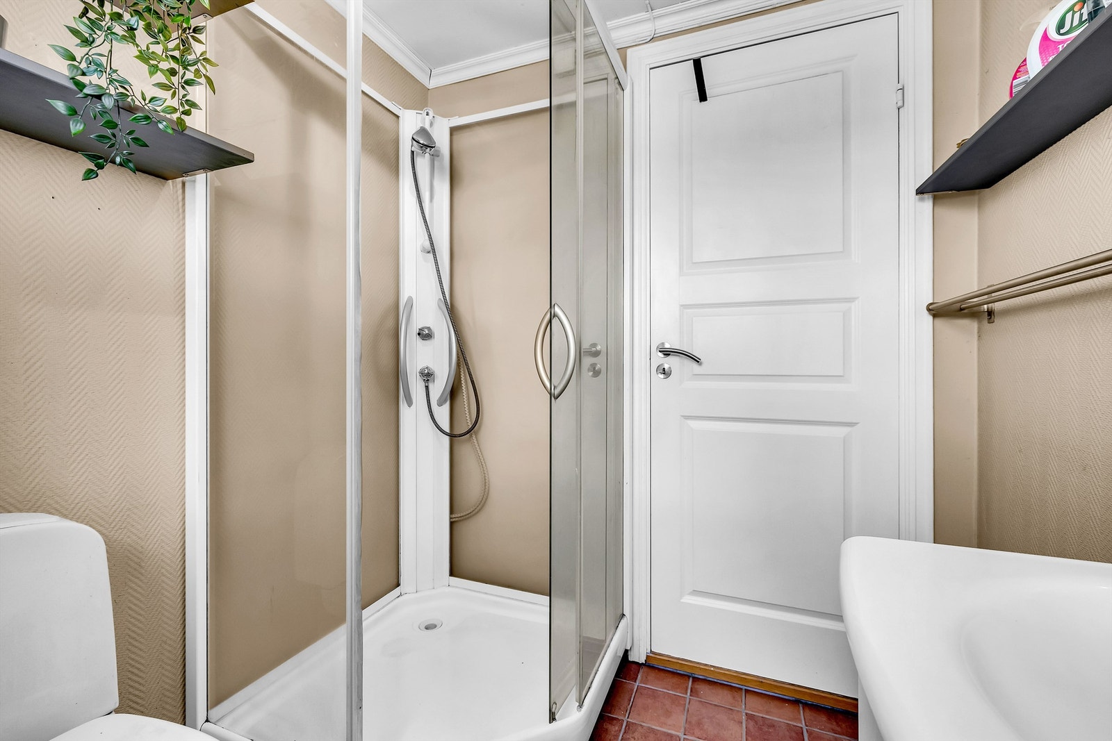 Badet har flislagt gulv med elektrisk gulvvarme, malte strievegger, heldekkende servant med underskap, dusjkabinett med glassdører og gulvmontert toalett. Galleribilde