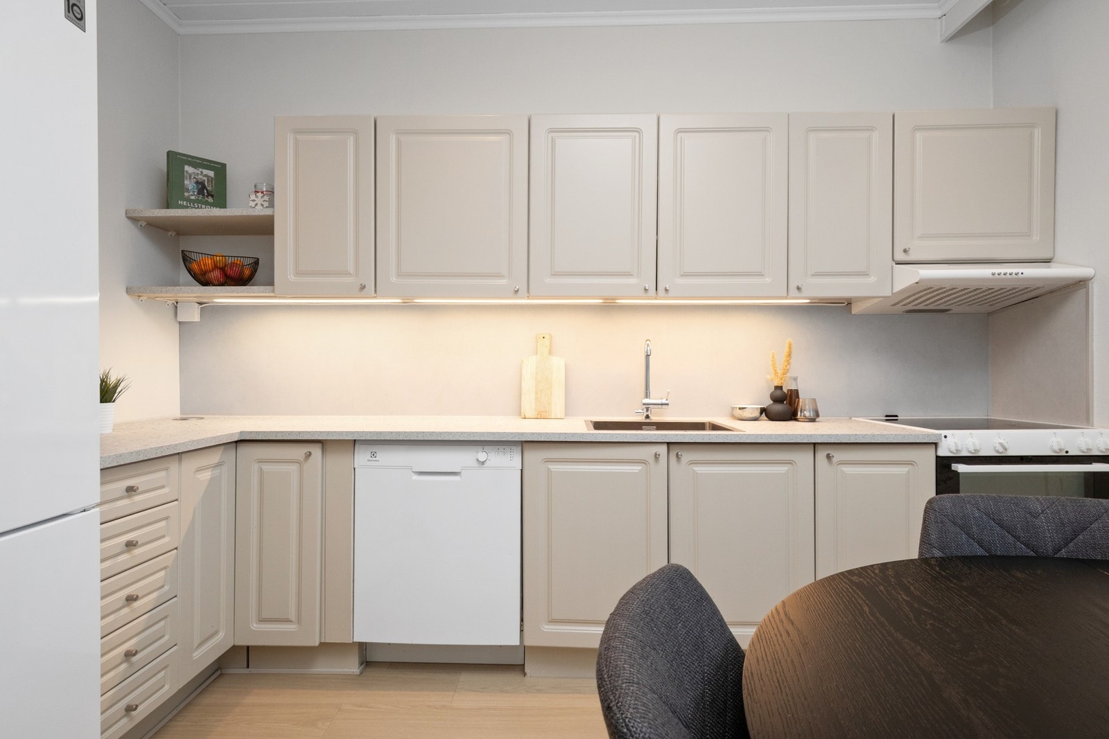 Innredningen står godt til veggene, med grå, profilerte fronter, pop-up stikk, nedfelt oppvaskkum og lys benkeplate av laminat Galleribilde