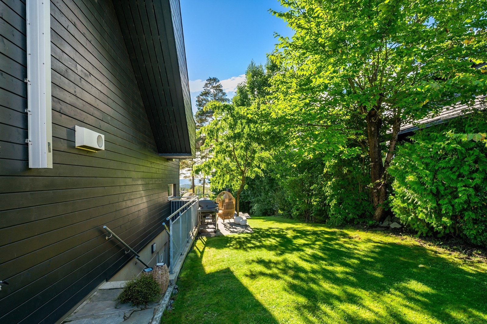 Tomten er pent opparbeidet med plen, busker og trær. Galleribilde