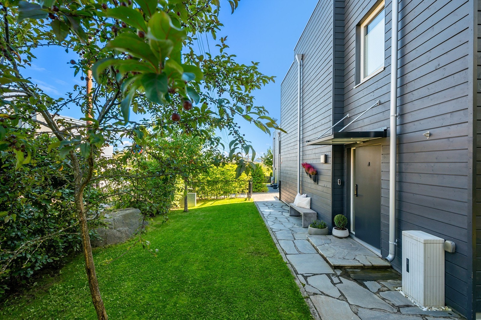 Boligens hovedinngang har et overbygd inngangsparti og en hellelagt gangsti. Galleribilde