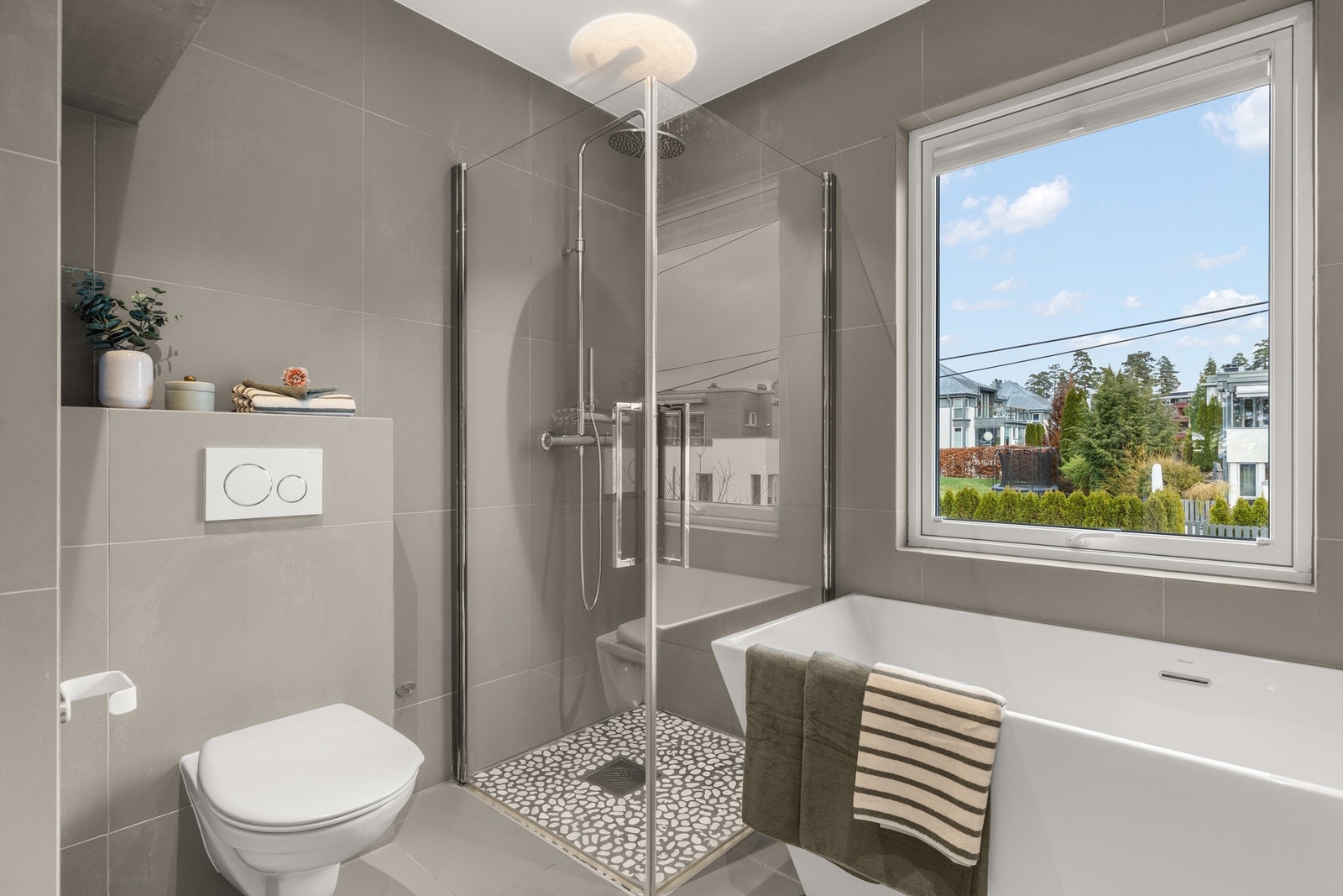 Dusjsonen har en elegant steindekor på gulvet og en regnfallsdusj. Galleribilde