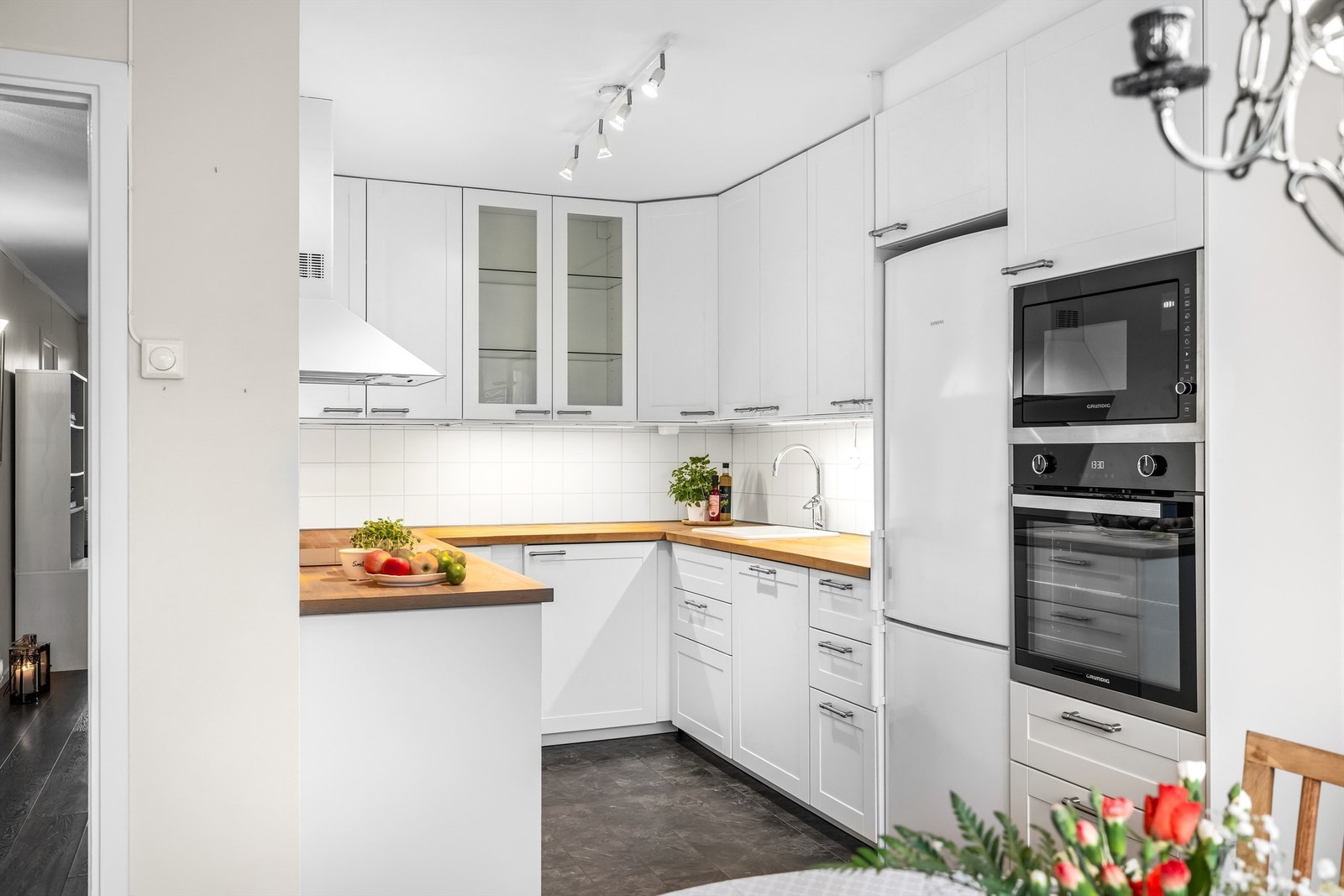 Kjøkkeninnredning med profilerte fronter, vitrineskap og rikelig med oppbevaringsplass. Galleribilde