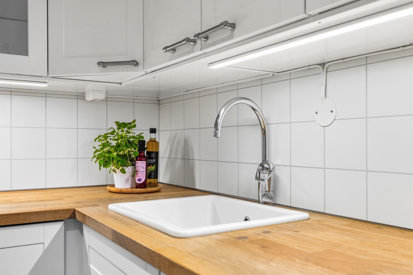 Detaljer som den nedfelte porselensvasken og benkeplaten i tre-utførelse gir kjøkkenet karakter. Galleribilde