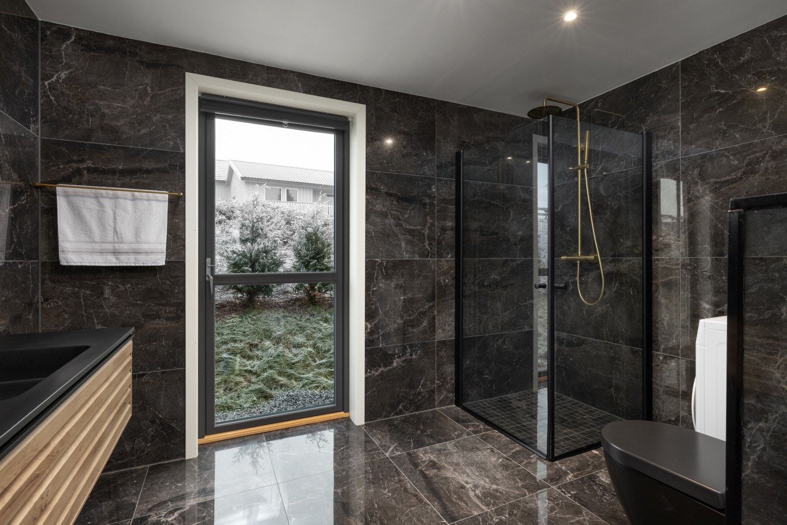 Badet er innredet med dusjhjørne, baderomsinnredning, speil, vegghengt toalett og opplegg for vaskemaskin Galleribilde