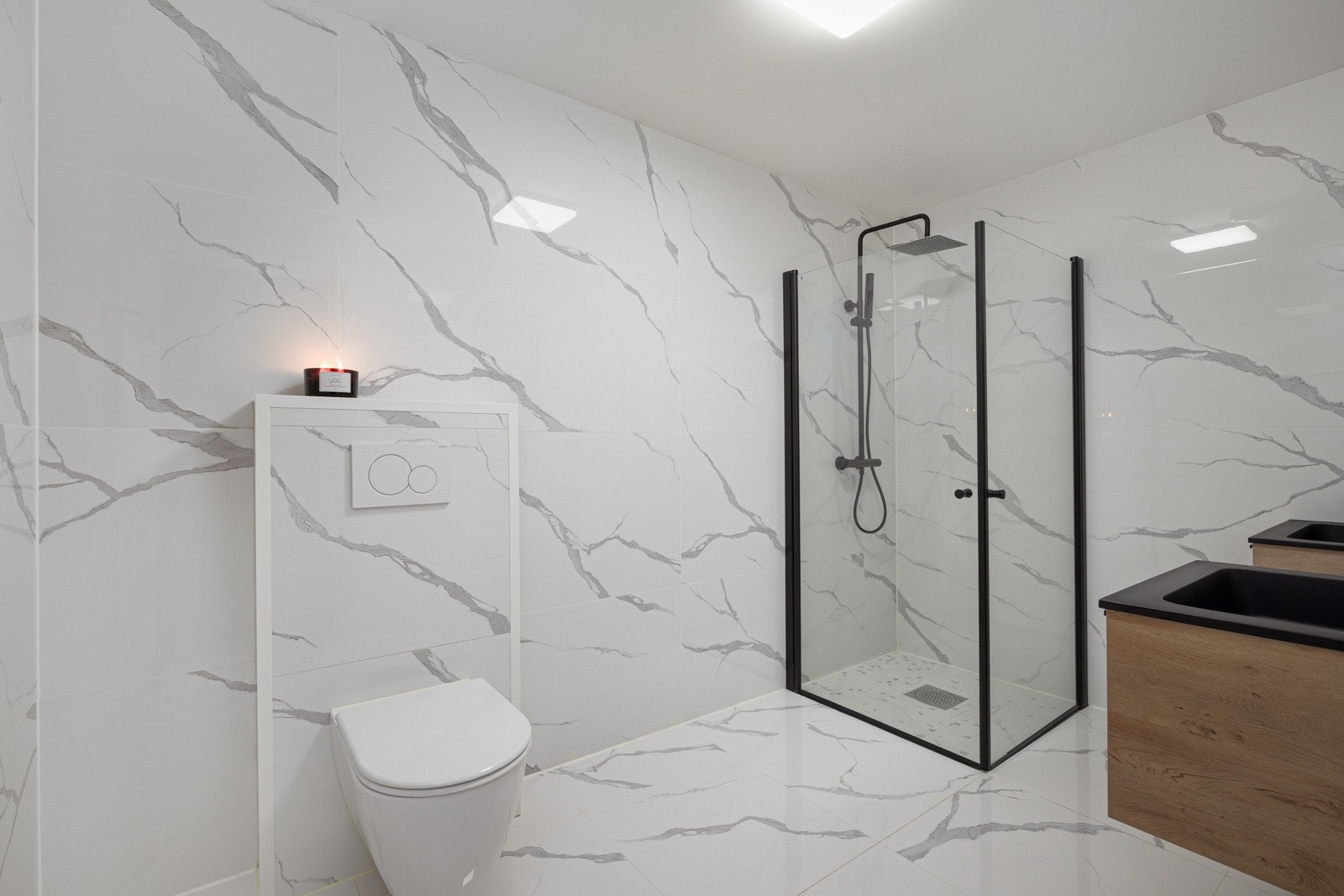 Badet er innredet med dusjhjørne, baderomsinnredning, speil, vegghengt toalett og opplegg for vaskemaskin Galleribilde