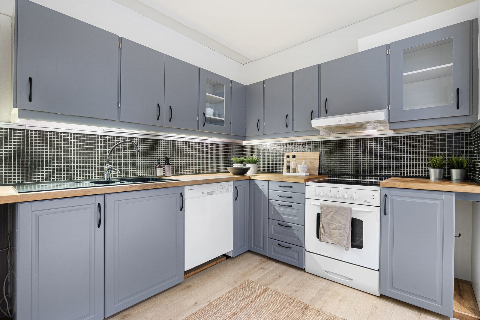 Sjarmerende kjøkken i L-form med rikelig skap og benkeplass. Galleribilde