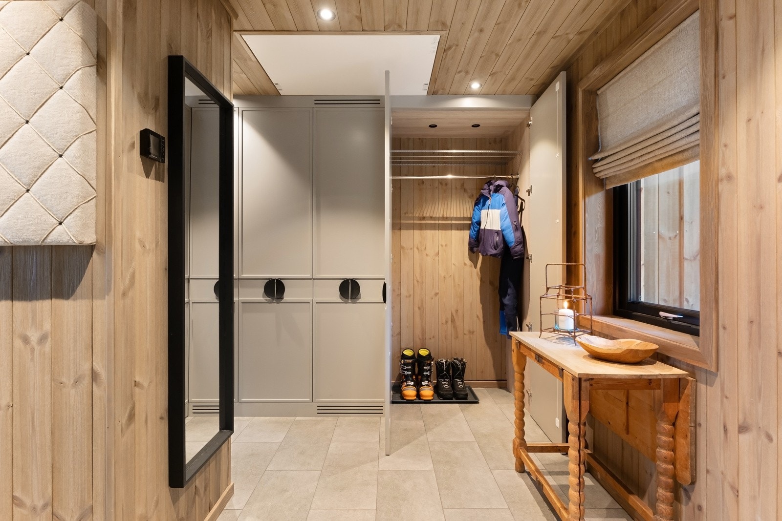 Vel inne blir vi ønsket velkommen i en langstrakt, pen entré med panel på veggene, downlights i himlingen og lysegrå fliser på gulv med vannbåren gulvvarme. Galleribilde