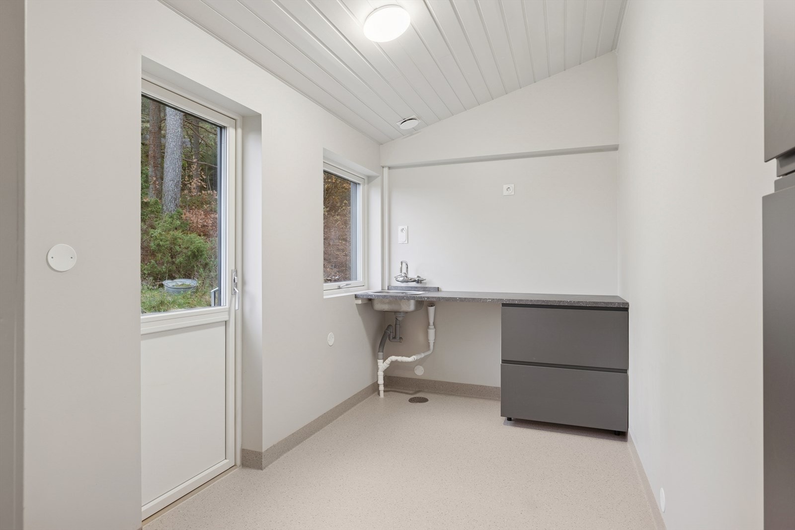 Praktisk vaskerom innenfor kjøkken. Rommet har utgang til hage, arbeidsbenk med vask og god plass til oppbevaring." Galleribilde