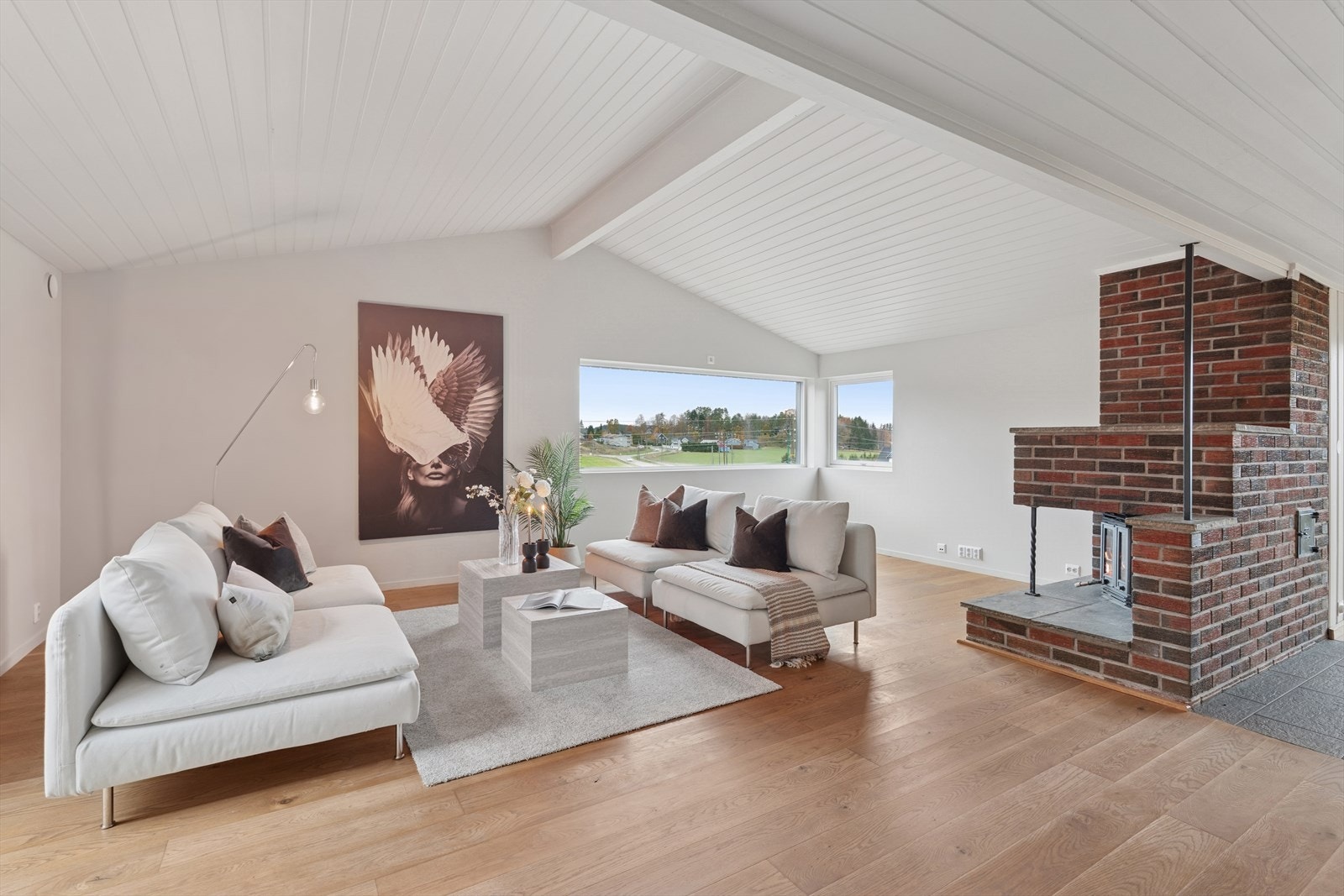 Lys og innbydende stue med store vinduer, god takhøyde og peis som gir en lun atmosfære. Galleribilde