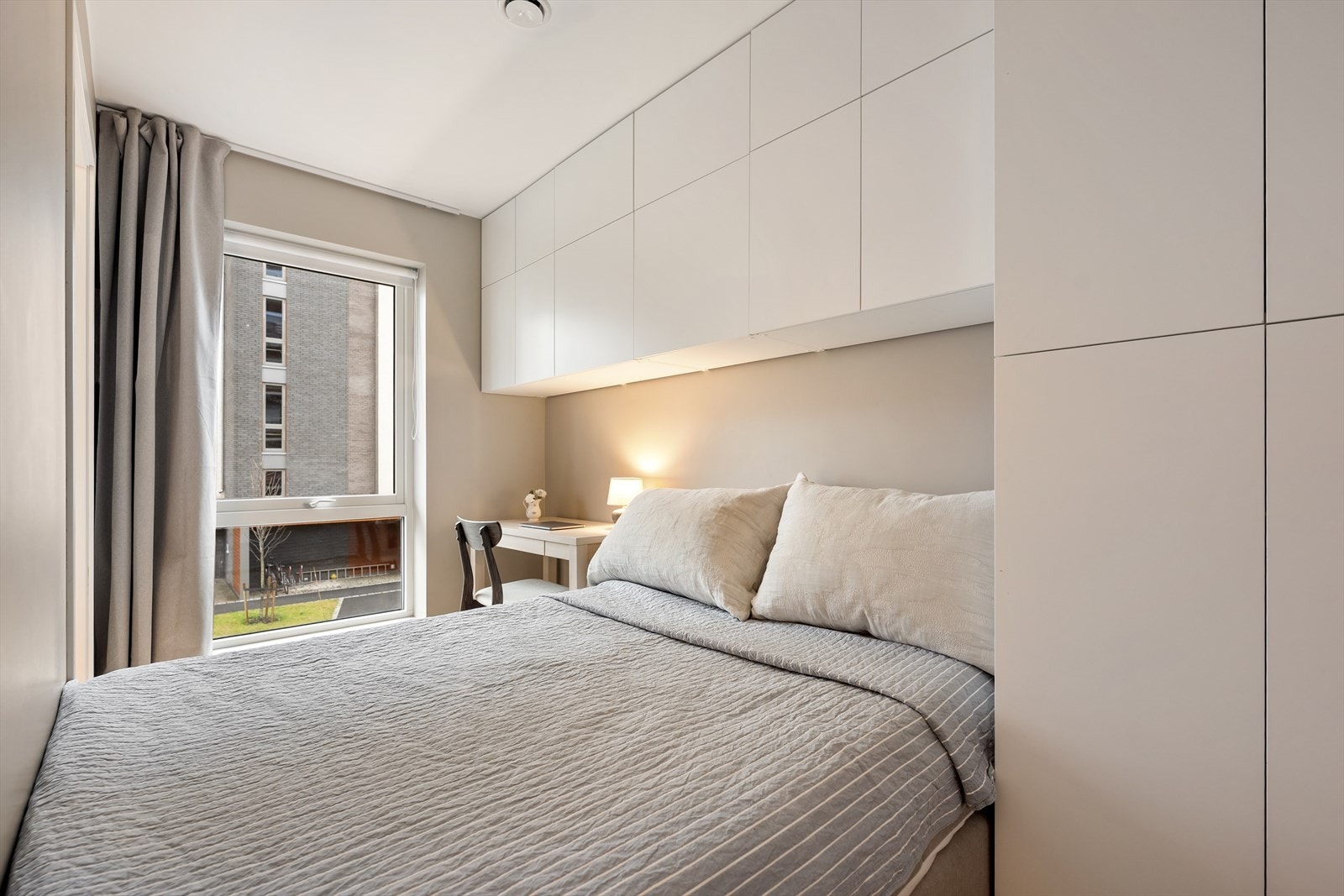 Hyggelig soverom med en praktisk oppbevaringsløsning og en liten arbeidsplass i hjørnet. Galleribilde