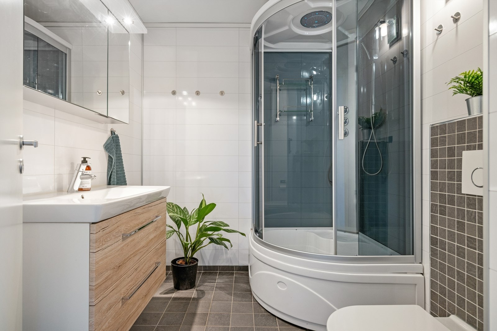 Baderommet er på 5m² og er utstyrt med servant med skuffer, speilskap, dusjkabinett og vegghengt toalett. Galleribilde