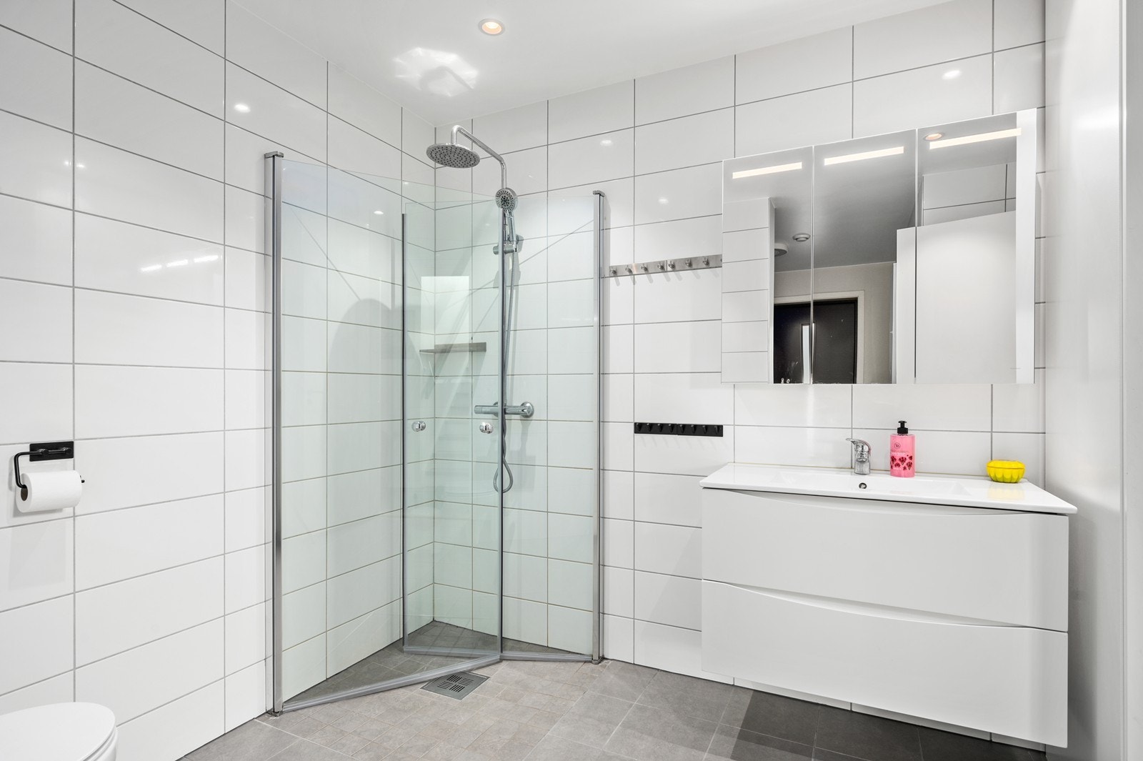 Baderommet er utstyrt med moderne innredning med dusjhjørne, servant med skap og vegghengt toalett. Galleribilde