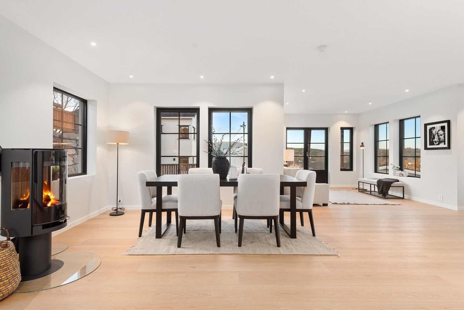 Dør med glassfelt leder videre inn til boligens hovedrom, en romslig og åpen stue- og kjøkkenløsning med store vindusflater og utstrakt bruk av downlights. Galleribilde