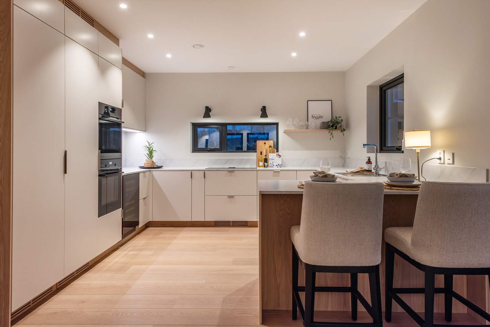 Halvøya gir ekstra arbeidsflate og skaper en naturlig overgang mot stuen, samtidig som den har plass til barstoler for uformelle måltider og hyggelige samlingspunkter. Galleribilde