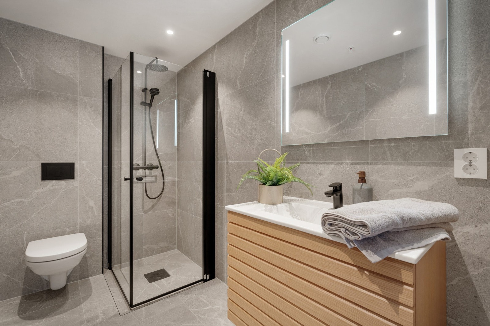 I andre etasje er det et nydelig bad med 60x60 fliser på gulv og vegger i Volterra Grey. Badet har gulvarme og innfelte downlights i himlingen. NB - Bildene er fra naboleiligheten. bygget. Galleribilde