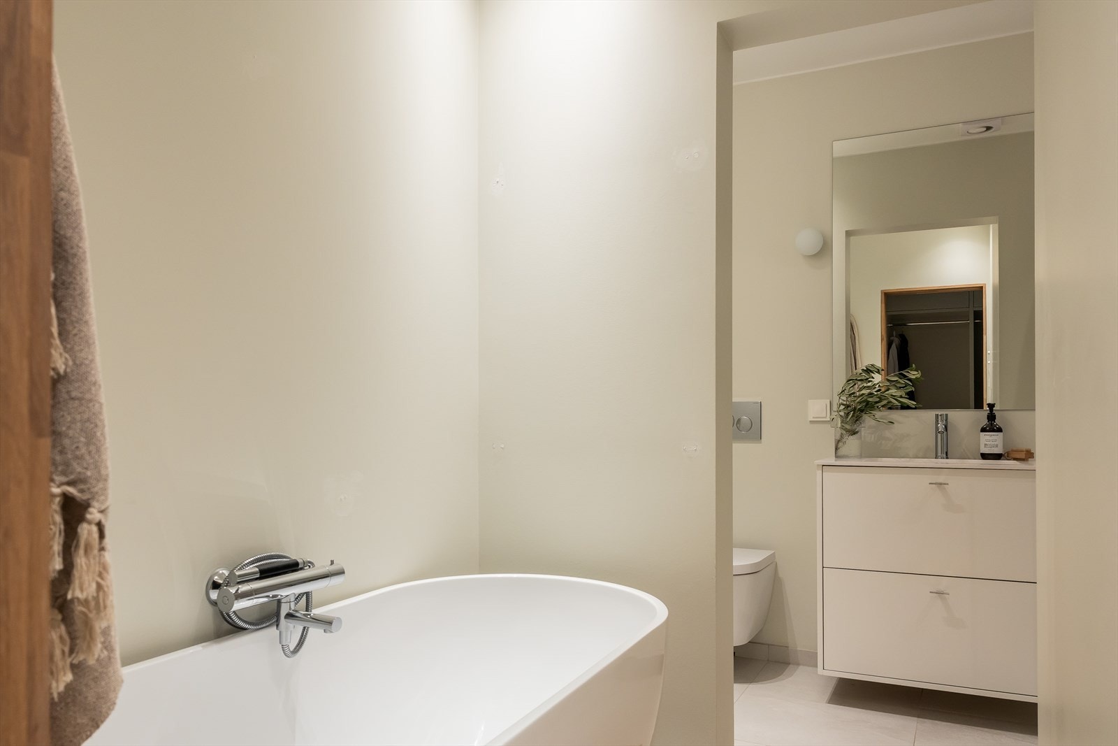 Bad en-suite pusset opp i 2020 med frittstående badekar og dusjnisje med dusjskillevegg i herdet glass. Vegghengt toalett og servantskap med speil på vegg. Galleribilde