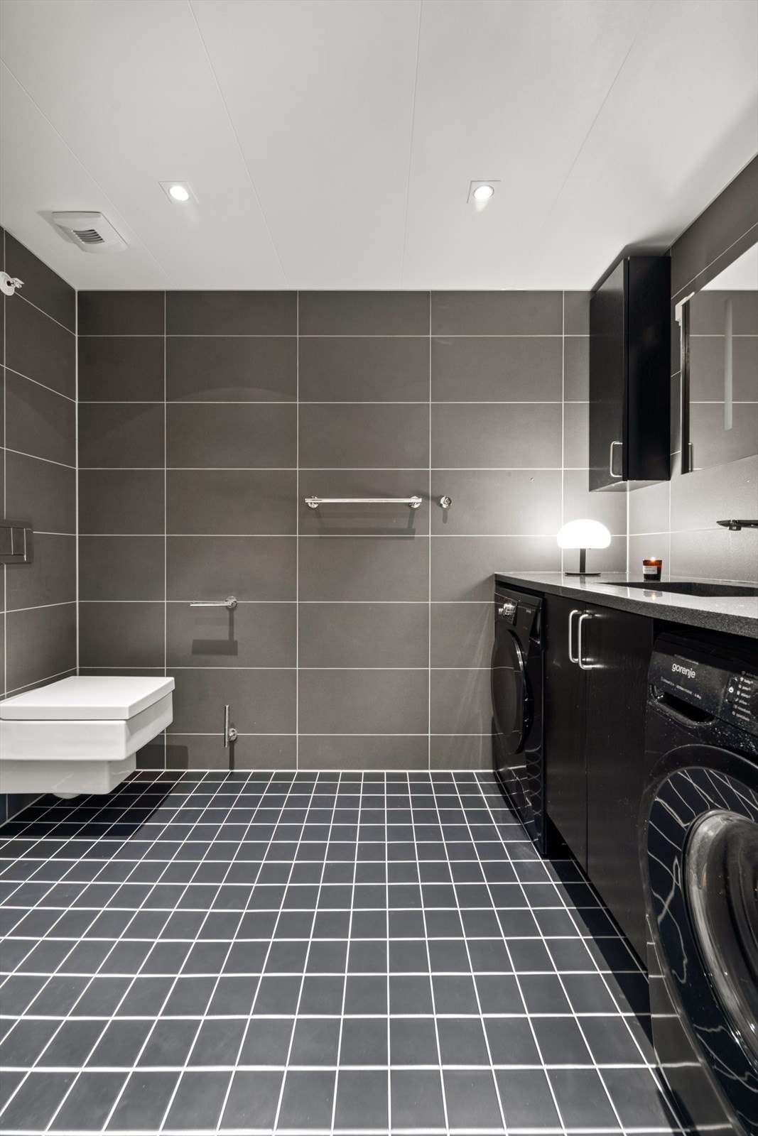 Delikat og flislagt bad i mørke toner med varmekabler i gulv. Galleribilde