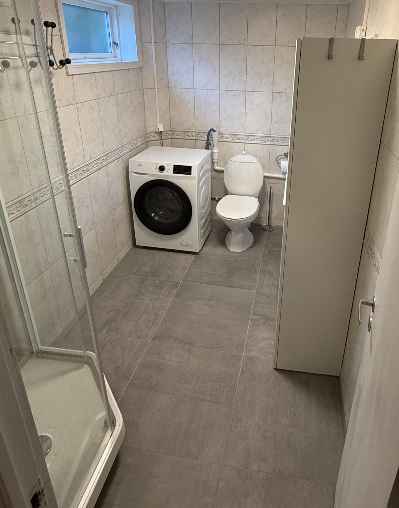 Badet har dusjkabinett og ny kombinert vaskemaskin og tørketrommel. Galleribilde