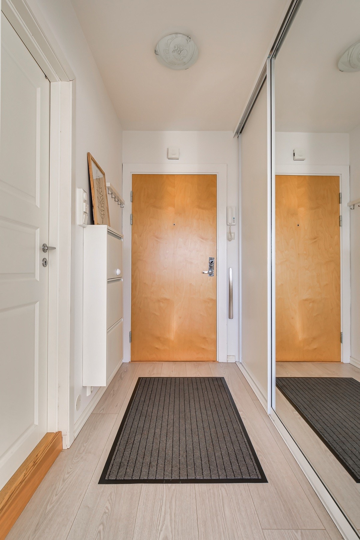 Innbydende entré med praktisk skyvedørsgarderobe som sikrer godt med oppbevaring Galleribilde