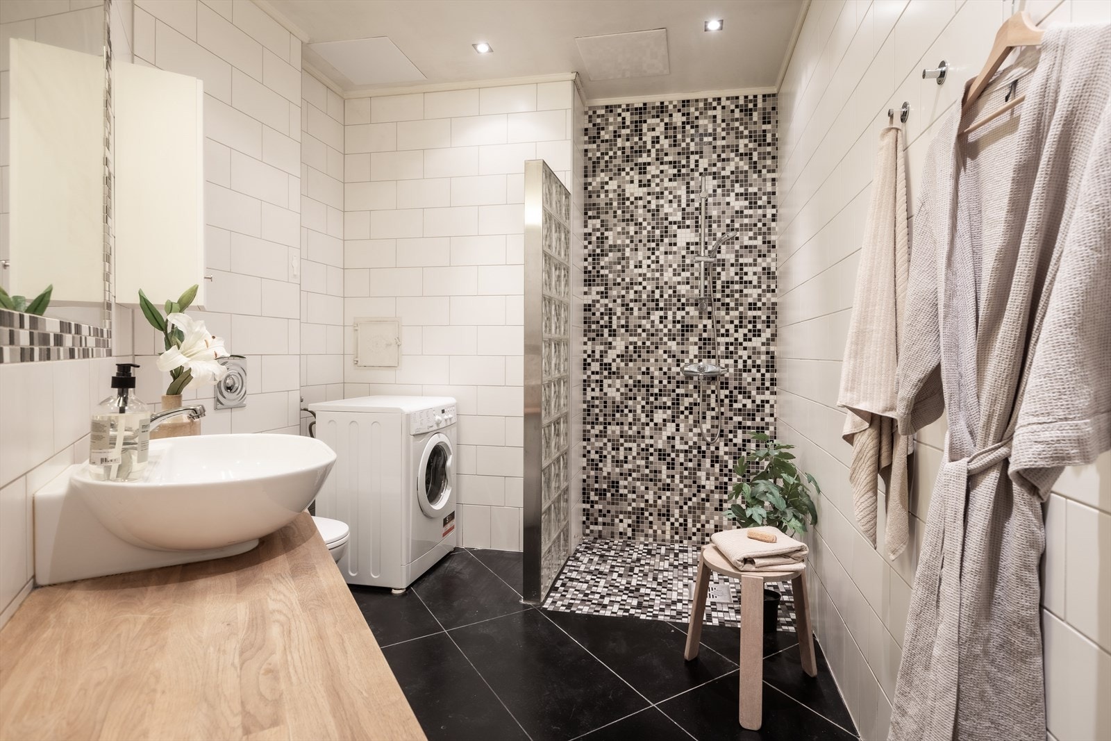 Romslig, flislagt bad fra 2006 med dusjnisje og opplegg for vaskemaskin og tørketrommel. Galleribilde