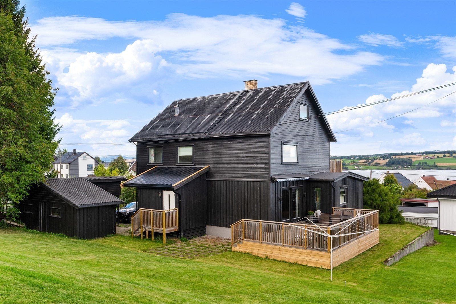 Fasade bakside med inngangspartier, terrasse, hage og utebod. Galleribilde